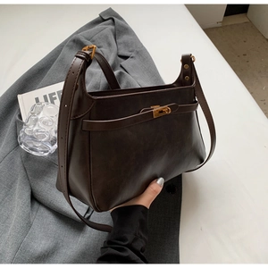 Dettaglio borsa vintage marrone con fibbia in metallo dorato e tracolla regolabile