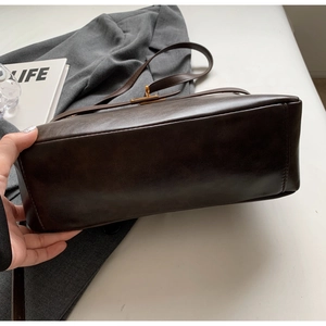 Dettaglio del fondo in pelle marrone scuro lucida e delle cuciture della borsa a spalla