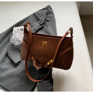 Dettaglio borsa vintage in pelle marrone opaca con chiusura girevole in metallo e fibbie