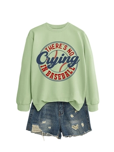 Flat lay of a green crewneck sweatshirt with retro baseball print and denim shorts