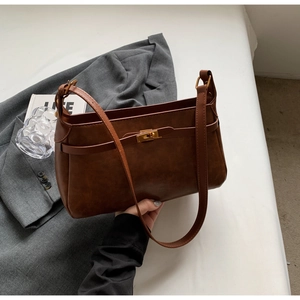 Dettaglio della borsa a spalla marrone vintage con fibbia dorata e cinturini in pelle