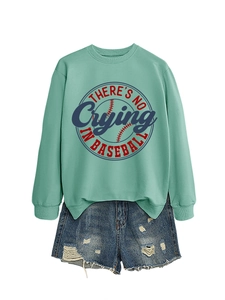 Flat lay of a mint green sweatshirt with 'There's No Crying In Baseball' and ripped denim shorts
