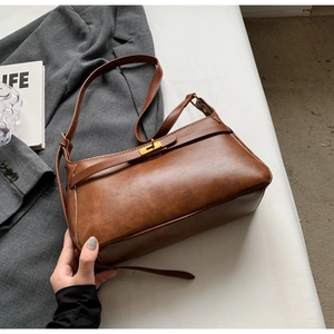 Dettaglio borsa vintage in pelle marrone con chiusura girevole dorata e abito formale