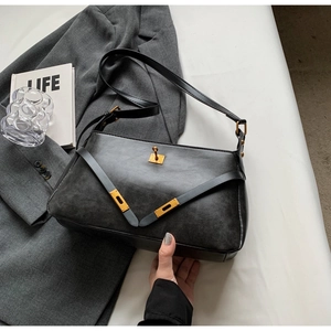 Dettaglio borsa a tracolla nera opaca su un blazer con oggetti di design lifestyle