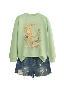 Dettaglio ravvicinato della felpa verde chiaro con stampa luna e fiori e pantaloncini in denim