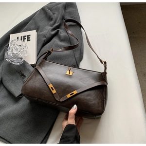 Dettaglio di borsa a mano in pelle marrone scuro lucido con chiusura girevole dorata