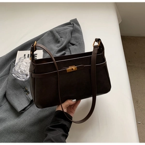 Dettaglio borsa a spalla vintage marrone scuro con fibbia dorata su giacca