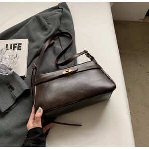 Dettaglio borsa retrò in pelle marrone scuro con fibbie dorate e decorazioni libri