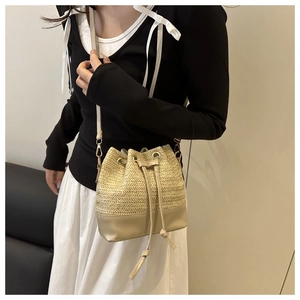 Détail du sac seau en paille avec cordon de serrage et base en cuir synthétique