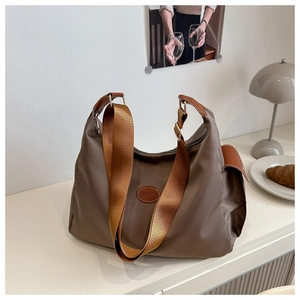 Dettaglio della borsa tote in nylon marrone caffè con logo in pelle e tracolla