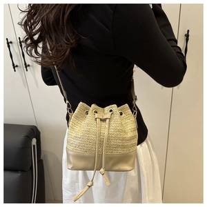 Détail de la texture tressée et base en cuir beige de ce sac seau en paille élégant