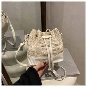 Détail du sac seau en paille avec tissage beige, bordure blanche et fermeture à cordon