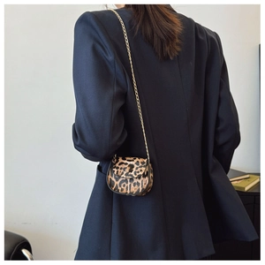 Detail einer Mini-Satteltasche mit Leopardenmuster und goldener Kette am Modell