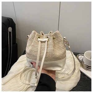 Détail d'un sac seau en paille tissée avec base en cuir blanc et fermeture à cordon