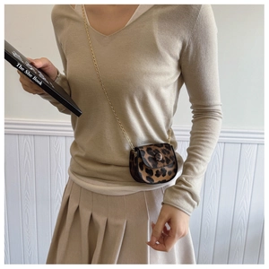 Nahaufnahme der Mini-Satteltasche mit Leopardenmuster und Metallkette an einem Model