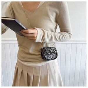 Detailaufnahme einer Mini-Satteltasche mit Leopardenmuster und goldener Metallkette