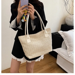 Lifestyle shot of large woven straw bucket bag with white faux leather handles