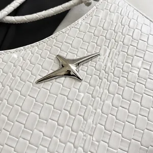 Macro detail of white woven leather texture with a silver star ornament on stylish bag