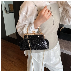 Detail of elegant black sequin evening clutch bag with gold chain strap on shoulder