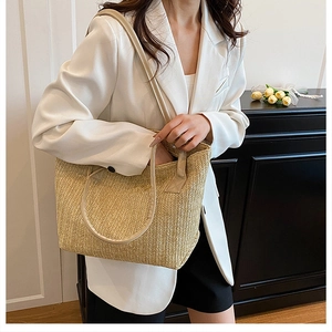 Detail showing the straw weave texture and long shoulder strap of this summer tote bag