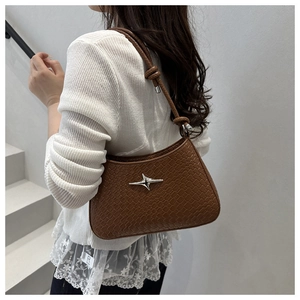 Détail d'un sac à bandoulière tressé marron avec fermoir étoile argenté et bandoulière