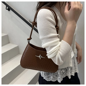Détail d'un sac sous le bras en cuir tressé marron avec boucle étoile en métal argenté