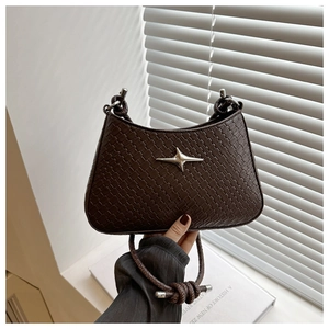 Détail d'un sac bandoulière tressé marron foncé avec étoile argentée et sangle torsadée