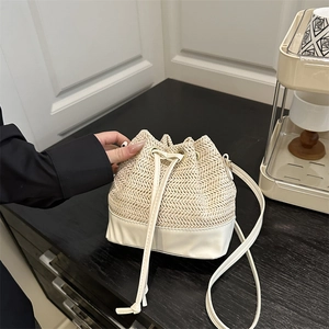 Sac seau chic en paille beige avec finitions en cuir blanc et fermeture à cordon