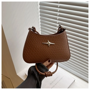 Détail du sac sous le bras tressé marron foncé avec boucle étoile et poignée nouée
