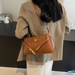 Borsa a tracolla retrò in pelle marrone con chiusura girevole dorata su una modella