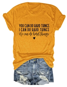 Detail of a yellow t-shirt with 'YOU CAN DO HARD THINGS' text and rolled cuffs