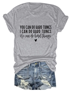 Flat lay of gray cotton T-shirt with 'YOU CAN DO HARD THINGS' text and denim shorts