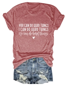 Flat lay of terracotta cotton t-shirt with white motivational text and ripped denim shorts