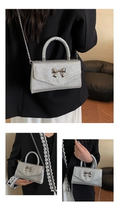 Detailed view of silver sequin handbag with metallic bow accent and chain strap