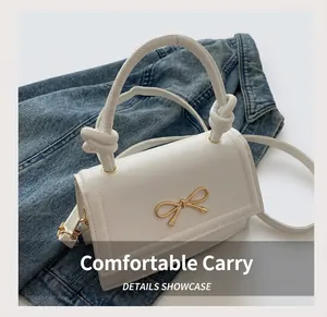 Dettaglio borsa in pelle bianca con fibbia a fiocco dorata e manico annodato di moda