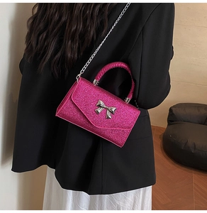 Close-up of glittery magenta crossbody bag with metallic silver bow detail on model