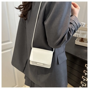 Vista lateral detallada de bolso bandolera blanco minimalista usado con blazer gris
