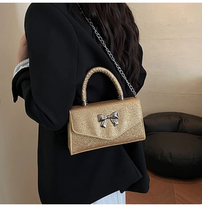 Detailed back view of a gold glitter mini bag with silver bow on a black blazer