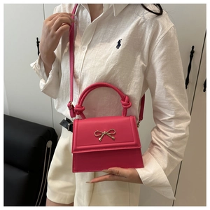 Dettaglio della borsa rosa con fibbia a fiocco dorata e manico a nodo elegante