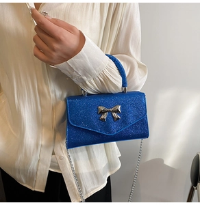 Detail of sequined electric blue mini bag with silver bow accent and chain strap