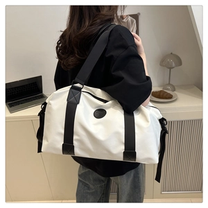 Modèle portant un grand sac de voyage bicolore avec larges bandoulières en intérieur