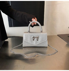 Detail of silver sequin crossbody bag with metallic bow and elegant chain strap