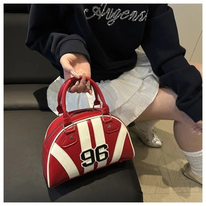 Detalle de bolso bowling rojo y blanco con parche 96 y adornos metálicos de estrellas