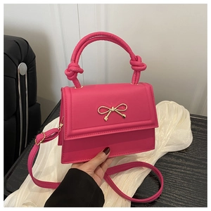 Dettaglio mini borsa rosa acceso con fiocco dorato e manico con nodo di design