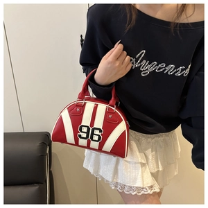 Detalle de bolso bowling rojo con rayas blancas y parche bordado con el número 96