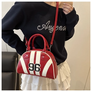 Bolso bowling retro rojo con raya blanca y parche número 96 usado como bandolera por una modelo