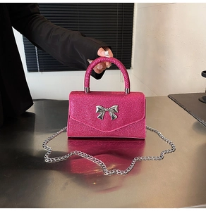 Detail of glittery pink handbag with silver bow buckle and elegant metal chain strap