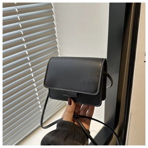 Detalle de un mini bolso cuadrado negro minimalista en cuero con correa para un estilo cotidiano