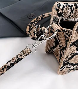 Detailaufnahme der Handtasche in Schlangenoptik mit Metallschnalle und Knotenschultergurt