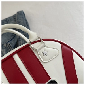 Detalle del bolso bowling rojo y blanco con remaches metálicos de estrella y asas de cuero